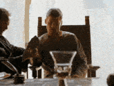 two men are sitting at a table with a glass in the middle