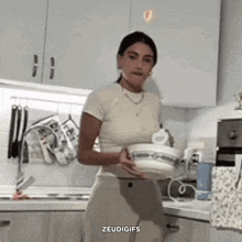 a woman is standing in a kitchen holding a bowl and says zeudigifs