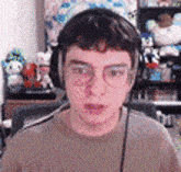 a young man wearing headphones and glasses is sitting in front of a computer screen .
