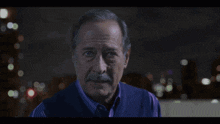 a man with a mustache is looking at the camera with a blurry background