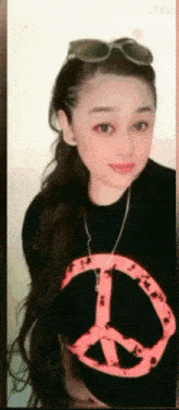 a woman wearing sunglasses and a black shirt with a pink peace sign on it