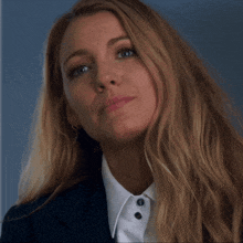 a woman with long blonde hair is wearing a white shirt and a suit