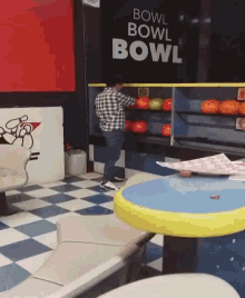 a man in a plaid shirt is playing bowling in a bowling alley