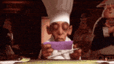 a cartoon chef is holding a piece of purple paper .