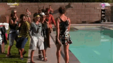 a group of people standing next to a pool with tv reality written on the bottom of the screen