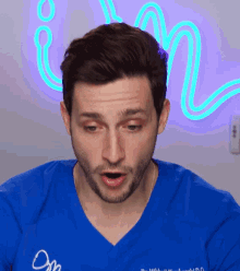a man wearing a blue scrub top that says " om " on it