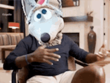 a man wearing a wolf mask is sitting in a chair with his hands outstretched .