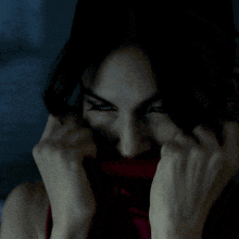 a woman covering her face with her hands and looking at the camera