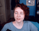 a woman with red hair is wearing a blue shirt and has a nose ring