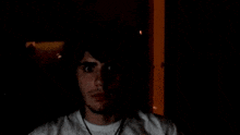 a man with long hair and a beard is holding his head in the dark .