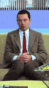 a man in a suit and tie sitting on a couch