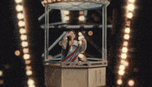 a man in a red white and blue striped shirt is standing in a ferris wheel