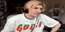 a man wearing headphones and a white t-shirt with the word go on it is standing in a room .