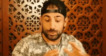 a man with a beard wearing a baseball cap and a necklace is talking .