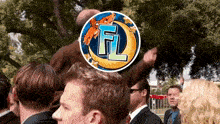 a man in a suit stands in a crowd with a circle with the letter f on it