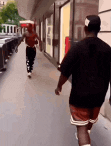 a man in a black shirt is walking down the street