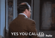 a bald man wearing glasses and a suit is standing in a room and saying yes you called .
