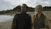 a man and a woman standing next to each other on the beach