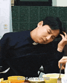 a man is sitting at a table with a bowl of food and says dude i 'm easy