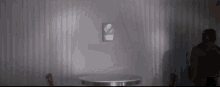 a man is standing in front of a table in a dark room with a clock on the wall .