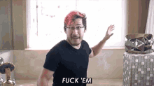 a man with red hair is standing in front of a window and saying fuck em .