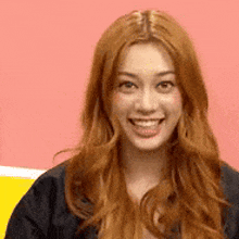 a close up of a woman with long red hair smiling .