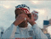 a man wearing a shirt that says england covering his face