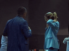 a man in a suit and tie standing next to a woman in a blue suit