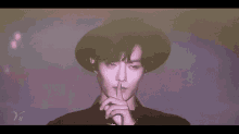 a young man wearing a black hat is making a hand gesture