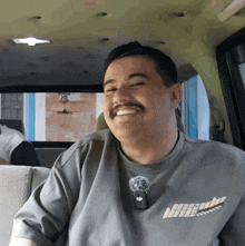 a man with a mustache wearing a gray shirt that says nasuda