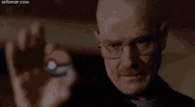 a close up of a bald man holding a red object in his hands .