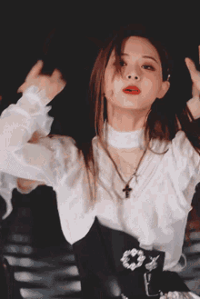 a woman wearing a white shirt and a black belt has a cross on her necklace