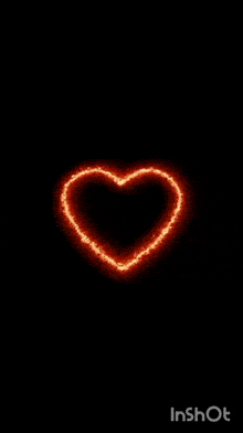 a heart made of fire is glowing in the dark on a black background .