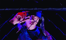 a person behind a chain link fence wearing a bandana and a blue hat