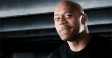 a bald man wearing a black shirt is smiling for the camera .