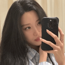 a woman is taking a picture of herself in the mirror with her phone .