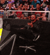 a man wearing headphones sits in a chair with his feet up in front of a crowd with one man wearing a free shirt