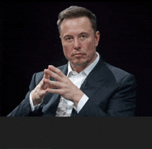 a man in a suit with his hands folded