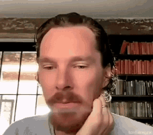 a man with a beard and a ring on his finger is looking at the camera .