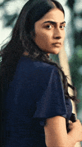 a woman in a blue shirt looks over her shoulder