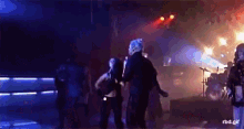 a group of people are dancing on a stage in a dark room with the words rbd.gif below them