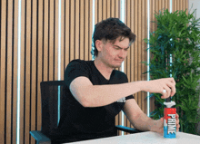 a man in a black shirt is holding a bottle of prime