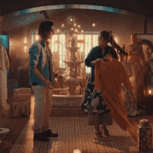 a man and a woman are standing in front of a fountain in a room
