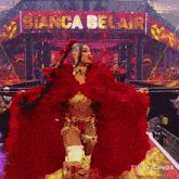 a woman in a red costume is standing in front of a sign that says " bianca belair "