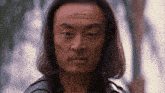 a man with long hair looks at the camera
