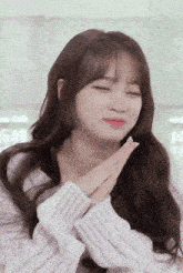 a woman with her eyes closed and her hands folded in front of her face