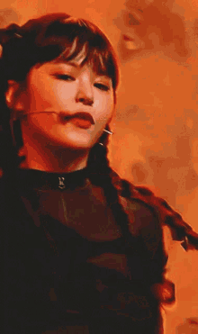 a woman is standing in front of a microphone on a stage wearing a braided ponytail .