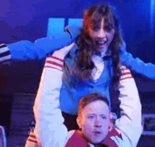 a man is carrying a woman on his shoulders in a theatre .