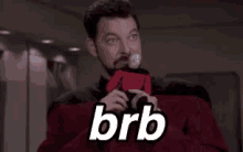 a man with a beard is holding a ball and the word brb is on his shirt .