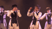 a group of men are singing into microphones on stage